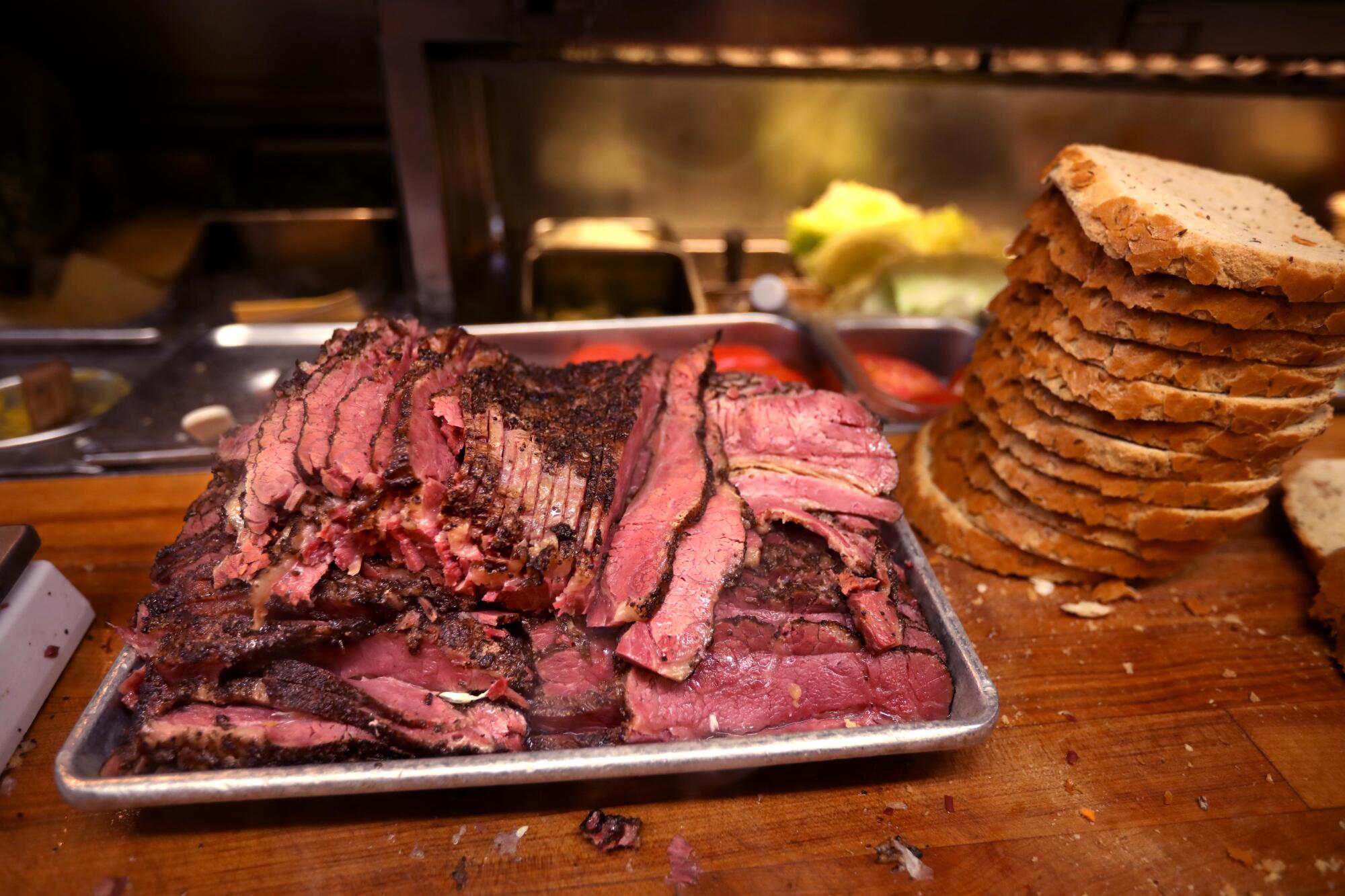 Stacks of pastrami and bread are ready to be made into sandwiches.