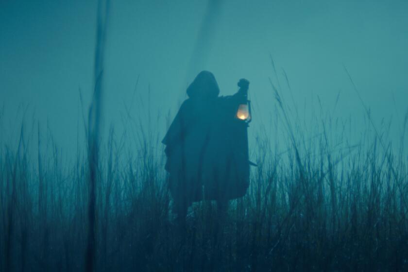 A cloaked figure in the fog holding a light