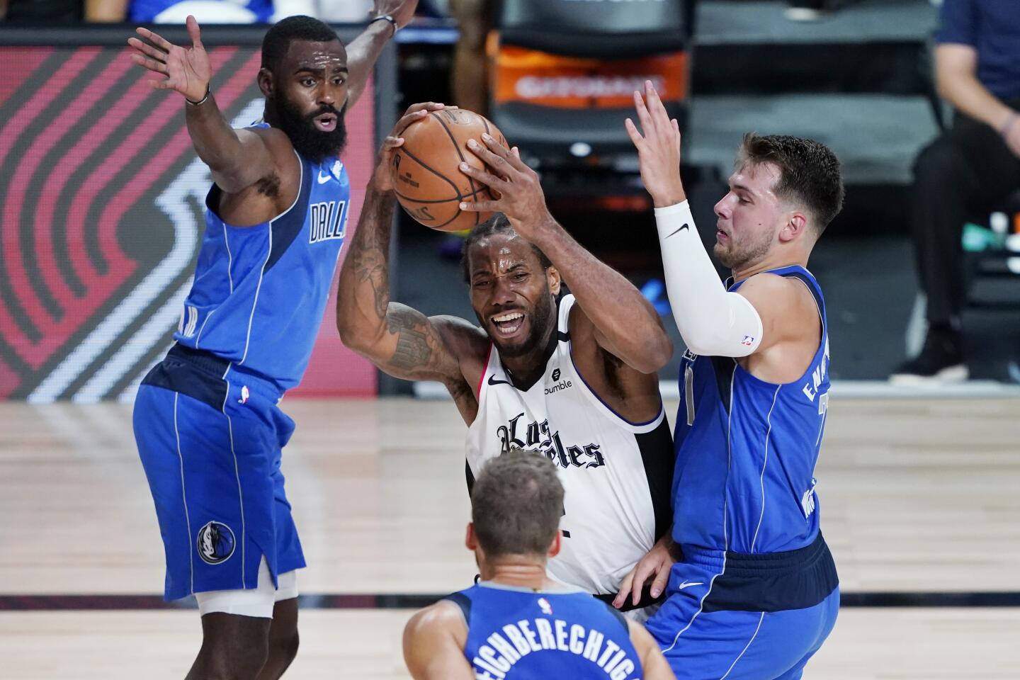 Clippers forward Kawhi Leonard, center, is pressured by Dallas Mavericks guard Luka Doncic, right, during the second half.