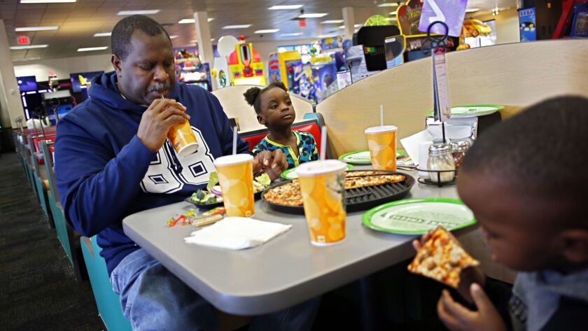 A man eats lunch with his grandchildren during a visit to a Chuck E. Cheese's in Dallas in 2014.