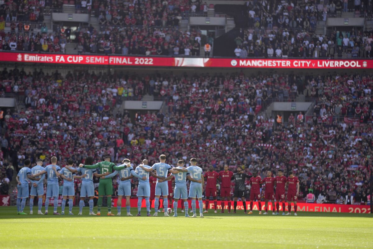 Manchester City, left, and Liverpool players stand for a moment of silence to remember those who died in the 1989 Hillsborough disaster, before the English FA Cup semifinal soccer match between Manchester City and Liverpool at Wembley stadium in London, Saturday, April 16, 2022. (AP Photo/Kirsty Wigglesworth)