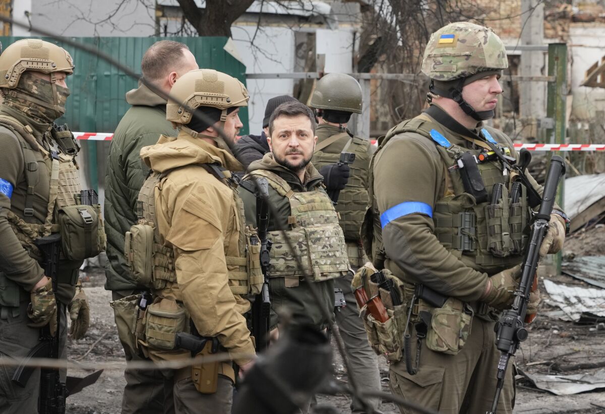 Ukrainian President Volodymyr Zelenskyy examines the site of a recent battle, in Bucha close to Kyiv, Ukraine, Monday, Apr. 4, 2022. Russia is facing a fresh wave of condemnation after evidence emerged of what appeared to be deliberate killings of civilians in Ukraine. (AP Photo/Efrem Lukatsky)