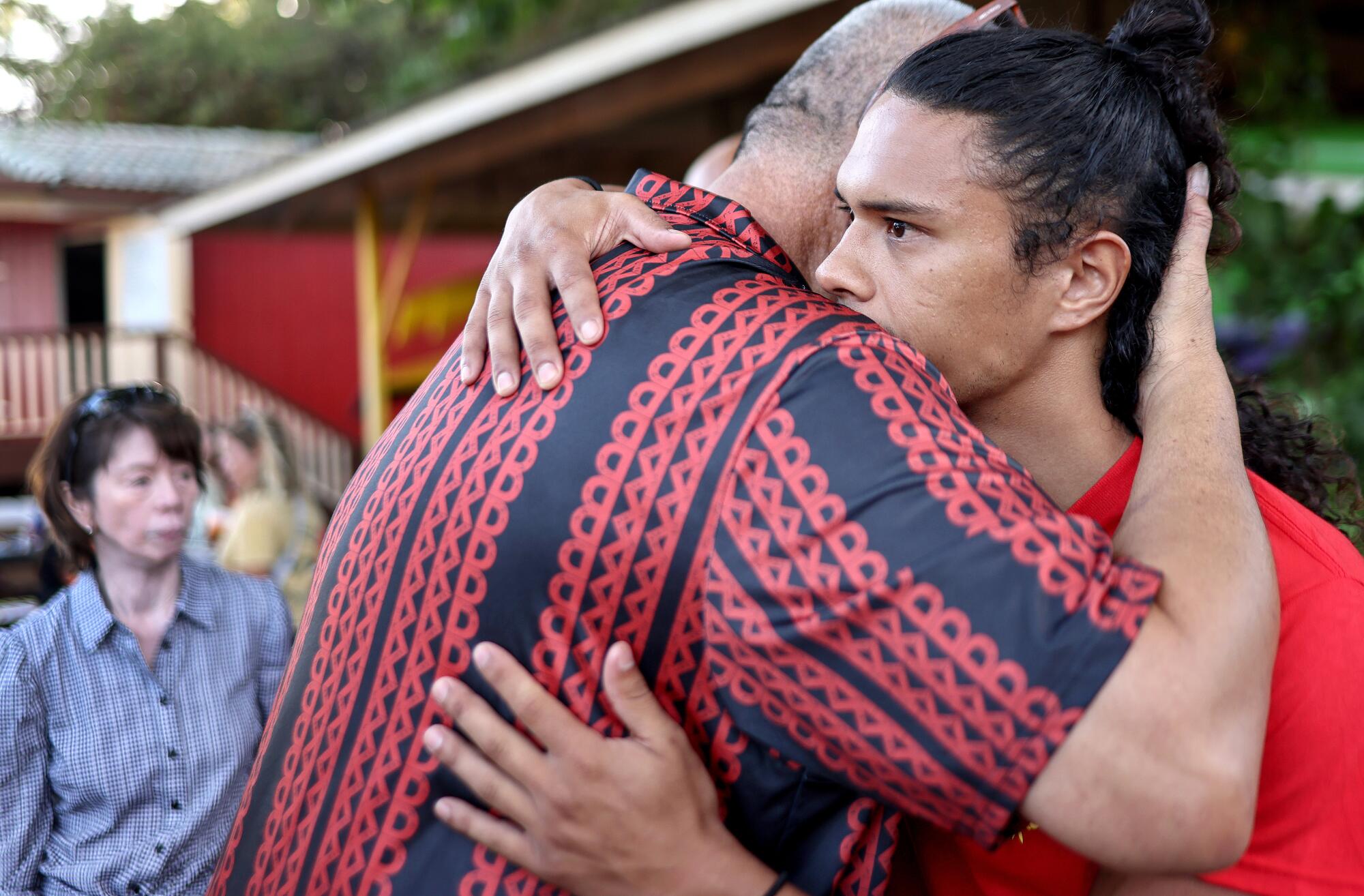Two men hug at a community gathering in Lahaina, West Maui, Hawaii.