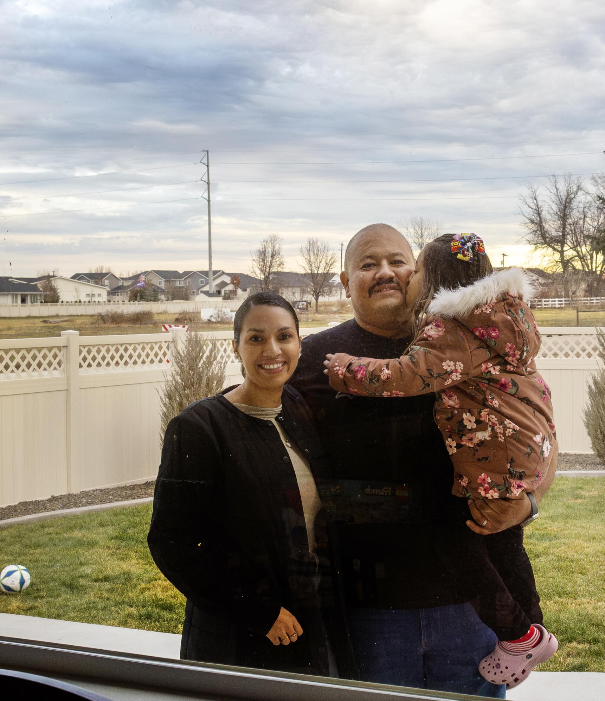 A family framed through the living room window of their rural home near Eagle, Ida.