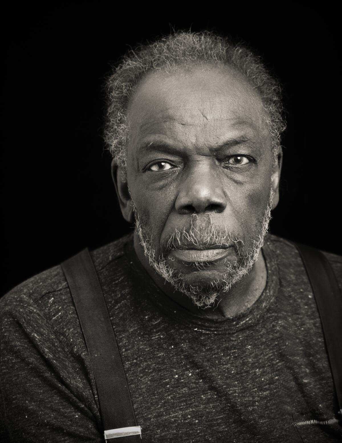 A man in suspenders poses for a portrait.