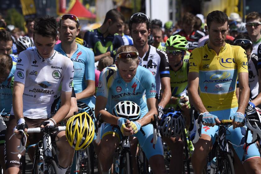 France's Romain Bardet wearing the best young's white jersey, Netherlands' Lieuwe Westra and Italy's Vincenzo Nibali wearing the overall leader's yellow jersey observe a minute of silence for the Malaysia Airlines plane crash, prior to the start of the thirteenth stage of the Tour de France.