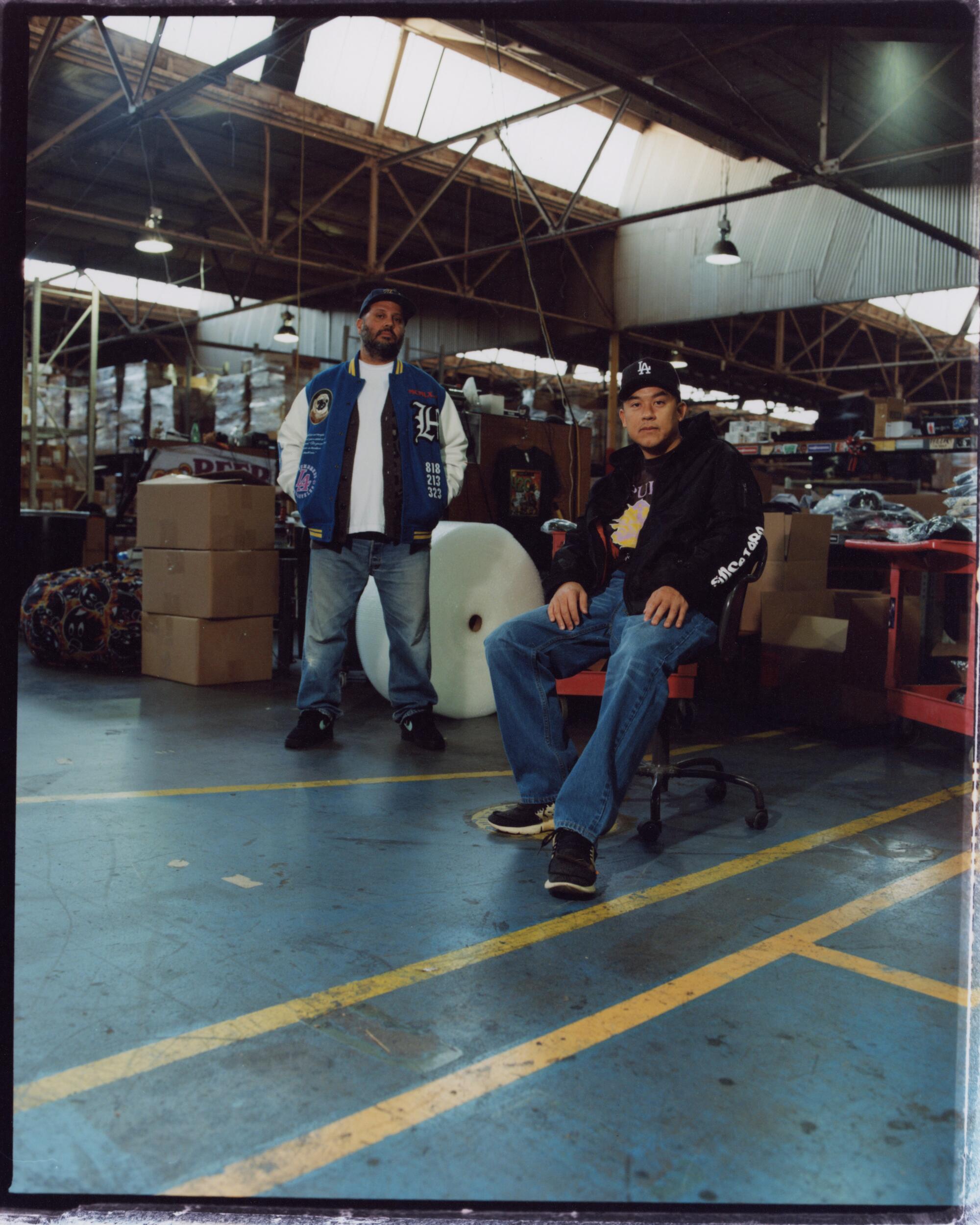 Two men in a warehouse filled with boxes and furniture