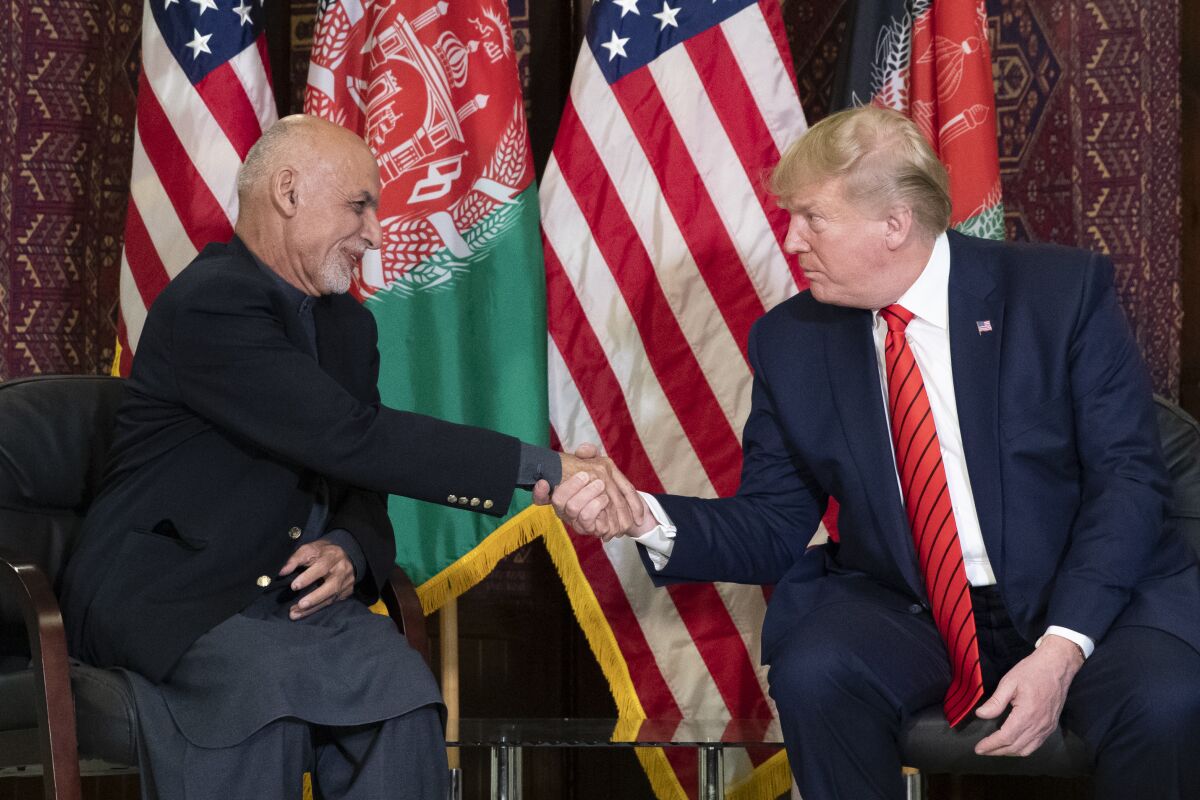 Afghan President Ashraf Ghani, left, and President Trump shake hands while seated in front of their nations' flags on Nov. 28, 2019.