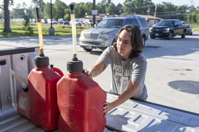Karla Espinoza Ortiz coloca recipientes de gasolina recién llenados en la parte posterior de su camioneta, en una gasolinera en Ford Road, después de que el huracán Beryl se abriera paso a través de Houston el lunes con categoría 1, el martes 9 de julio de 2024, en Houston. (Jason Fochtman/Houston Chronicle vía AP)