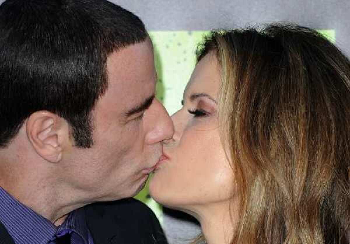 John Travolta and his wife, Kelly Preston, kiss as they arrive for the premiere of Universal Pictures' "Savages" at Westwood Village.