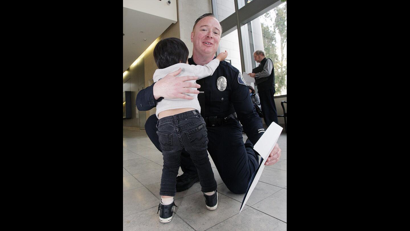 Clayton Cha, 3, of Glendale, runs into the arms of Glendale Police Officer James Colvin to say goodbye after meeting with him to thank him at the Glendale Police Department on Thursday, Jan. 22, 2016. Last April, Colvin was the first on the scene to treat then 2-year-old Clayton, who had fallen on his head from 22-feet onto concrete.