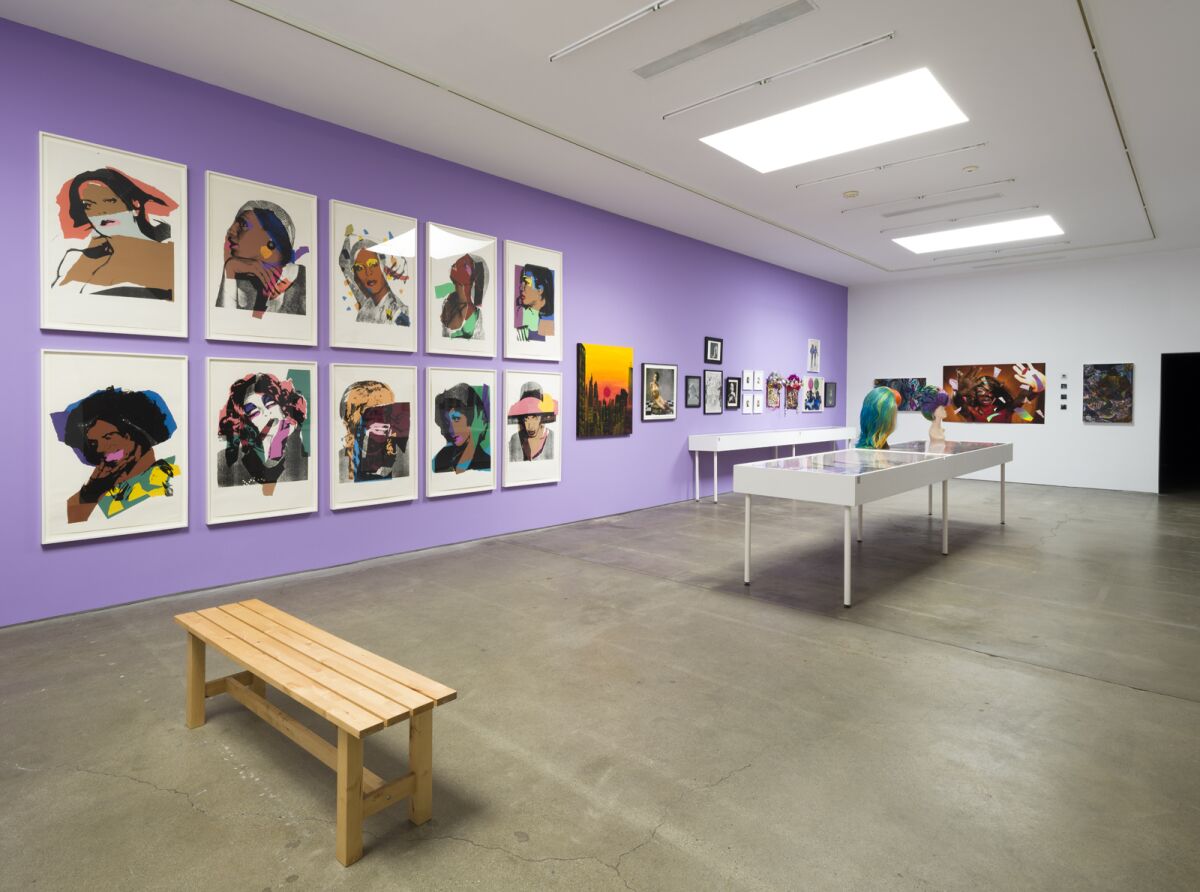 A gallery with a bright lavender wall displays prints by Andy Warhol, among other artists