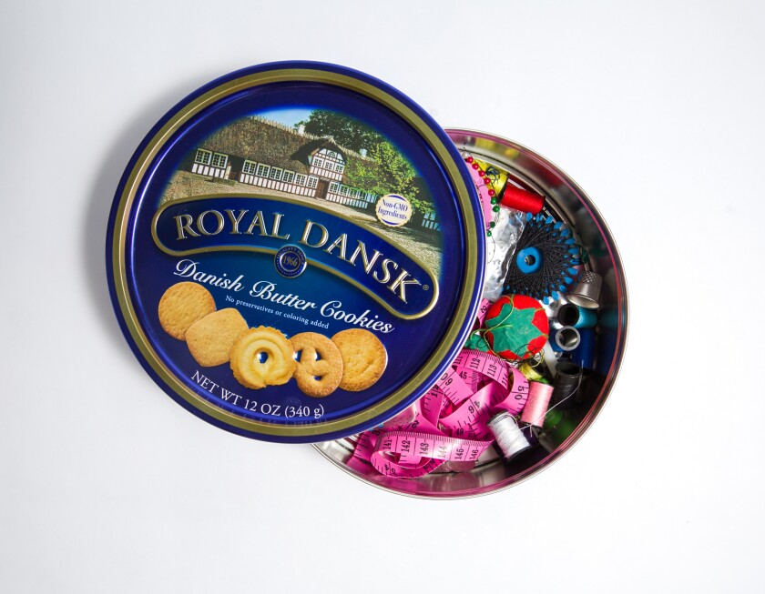 A Royal Dansk cookie tin is seen full of sewing supplies.