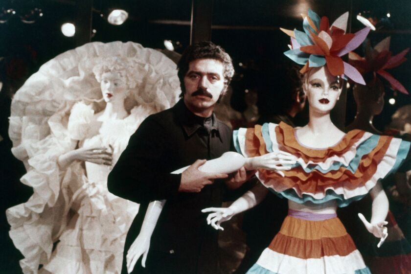 A man flanked by two mannequins wearing paper dresses