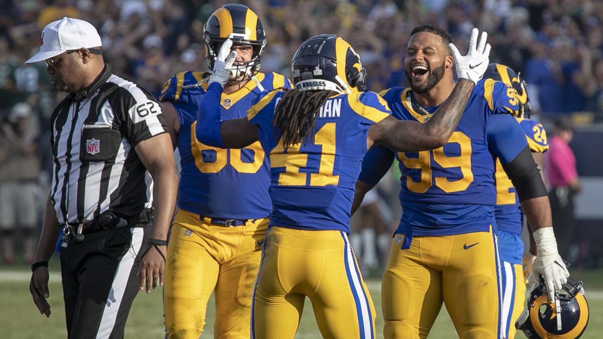 Austin Blythe, left, Marqui Christian, center and Aaron Donald, right, celebrate after Packers Ty Montgomery fumbled a kickoff return late in the fourth quarter to seal the Rams win and extend their undefeated season.