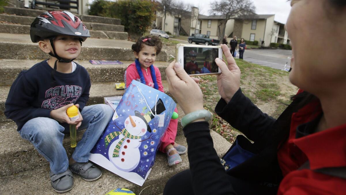 Volunteer Jessica Yang takes a photo of newly arrived Syrian refugee siblings Majerid, 7, left, and Jory, 4, after presenting them with gifts outside their family's apartment in Dallas in 2015.