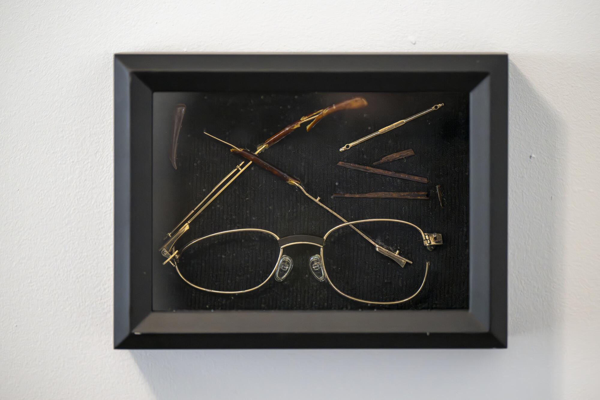 A broken pair of glasses in a frame.