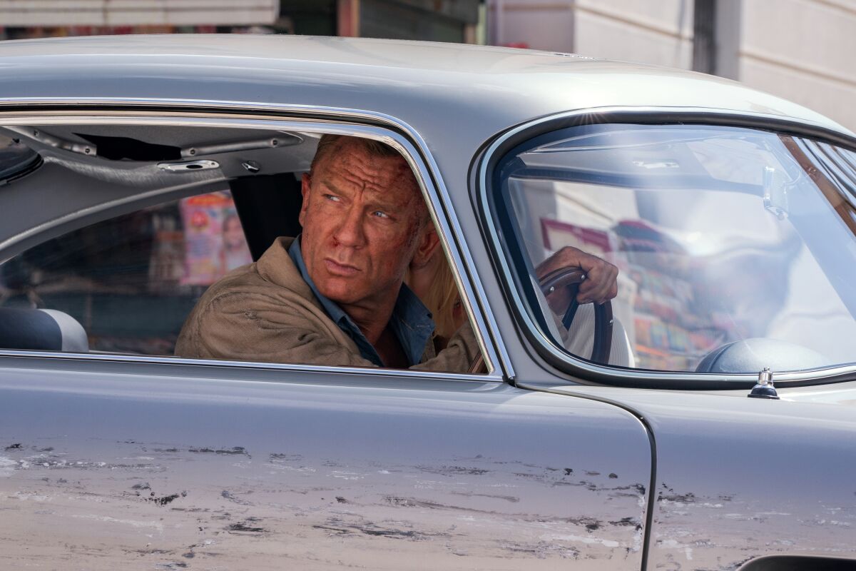 A beat-up man looks out the window as he drives a car
