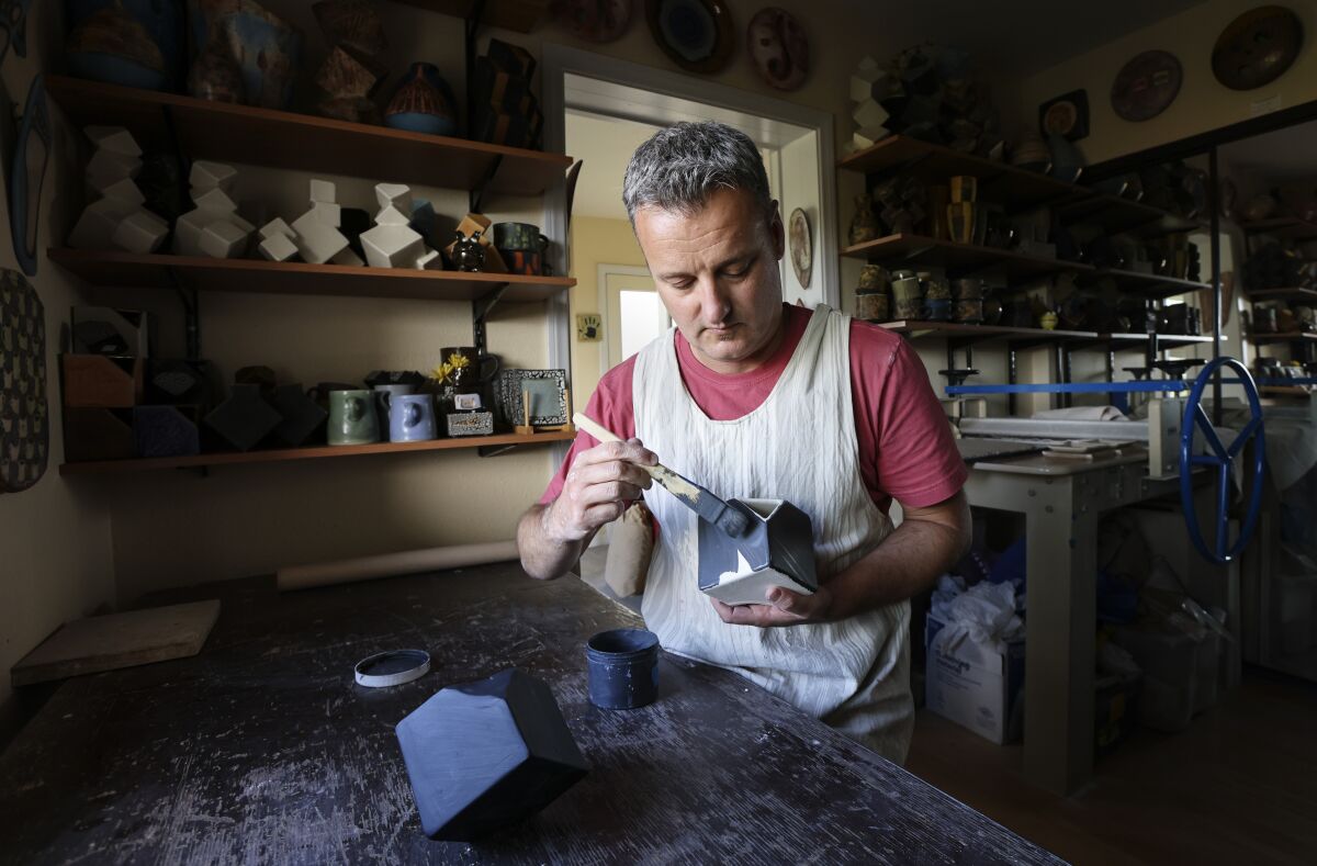 Ceramic artist Pierre Bounaud brushes glaze onto a cube at his home studio in Talmadge.
