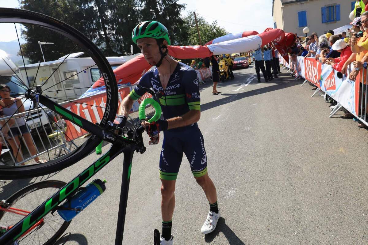 Adam Yates walks with his bike after being knocked down by a fallen inflatable arch during Stage 7 of the Tour de France.
