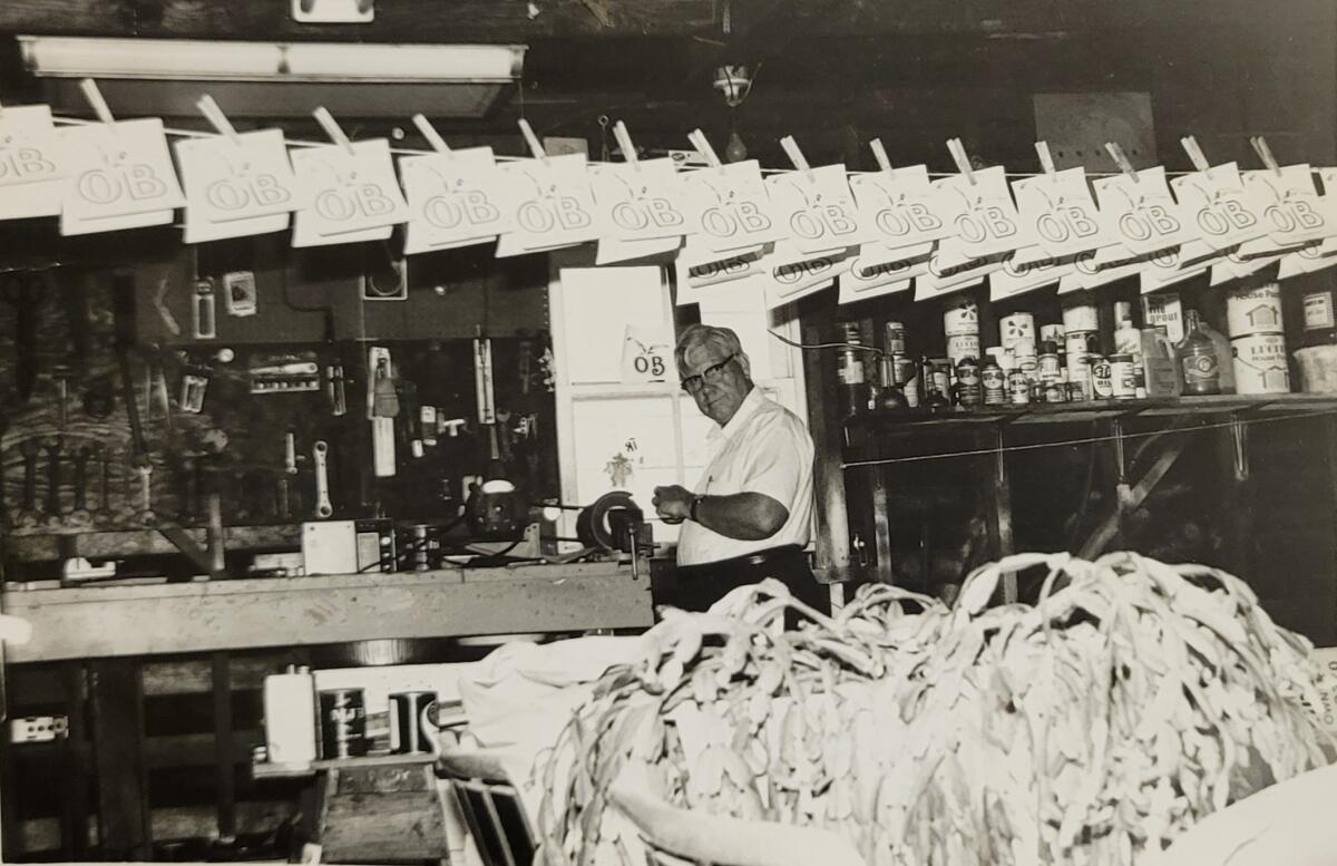 Donald Sorben pins some of son Bob’s silk-screened logos on a clothesline in the garage of the family home in Point Loma.