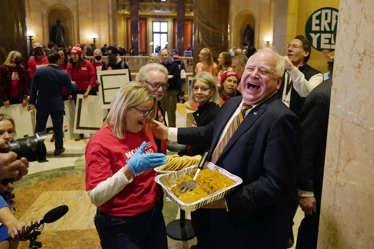 Minnesota Gov. Tim Walz, right, hands out pumpkin bars to a gun safety advocate.