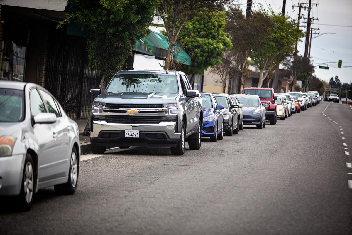 A long line forms outside of Masataco in Whittier as customers wait in their vehicles for their turn to shop for grocery items and the much needed KN95 on April 7.
