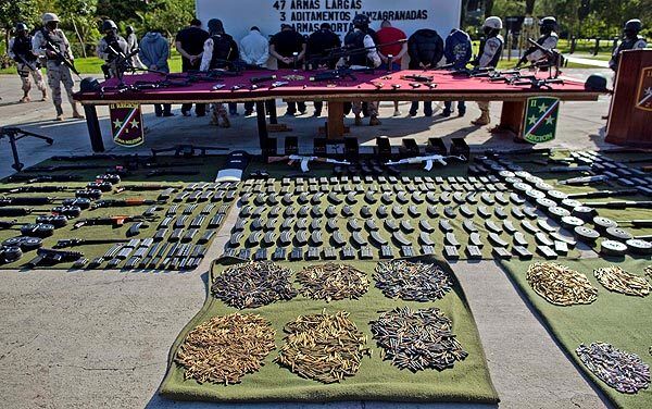Weaponry and suspects are on display in Tijuana after authorities conducted raids in two neighborhoods.