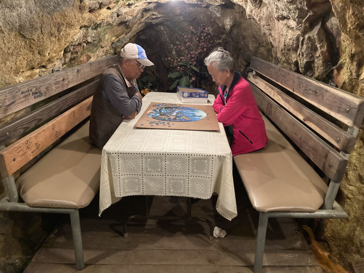 A couple sits at a booth inside a mine, working a puzzle