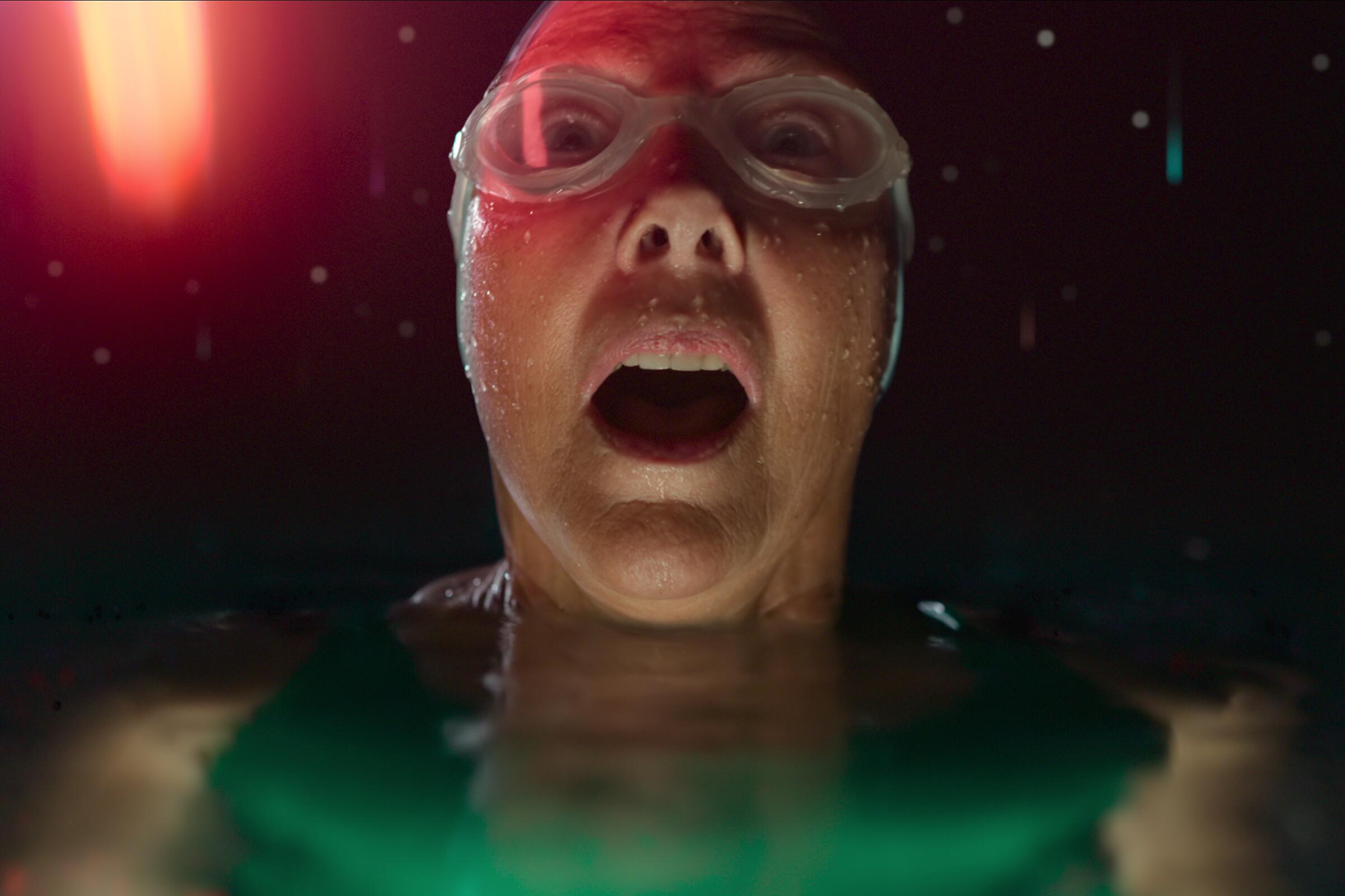 In a scene from "Nyad," Annette Bening lifts her head out of the water to see colorful lights descending from the night sky.