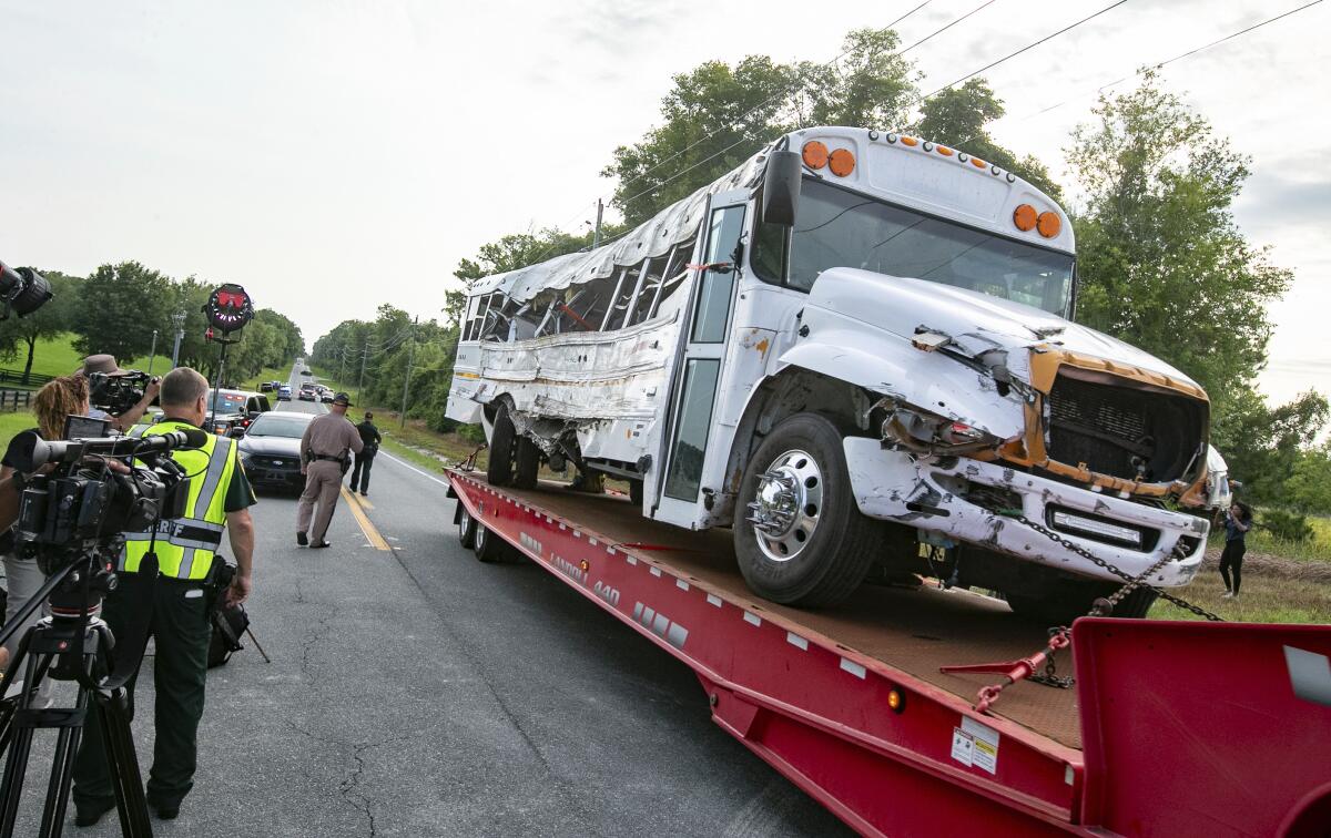 A damaged bus is loaded onto a trailer for removal.
