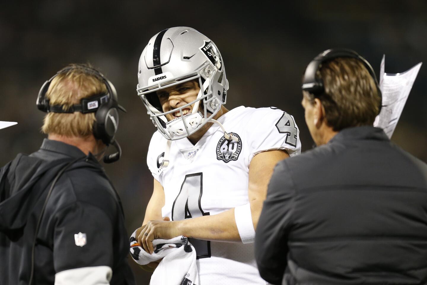 Raiders quarterback Derek Carr (4) talks with coach Jon Gruden, left, and offensive coordinator Greg Olson during the first half of a game against the Chargers on Nov. 7 at RingCentral Coliseum.
