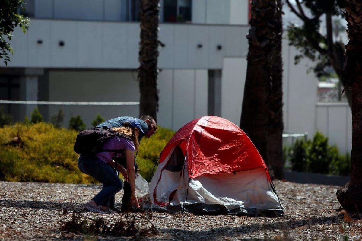 Outreach workers speak to a homeless person in their tent in downtown Los Angeles on June 28, 2019.