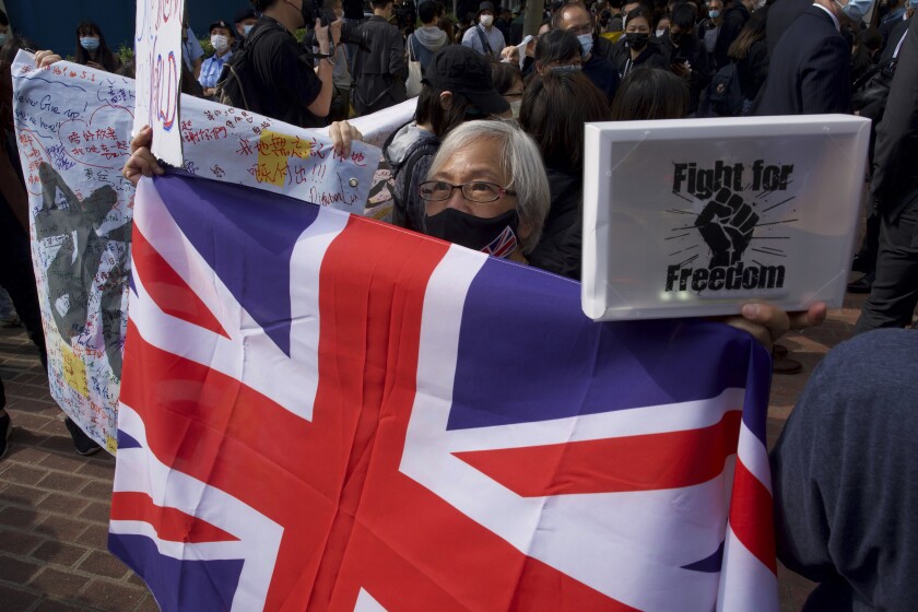 A supporter raises a British flag as supporters queue up outside a court to try get in for a hearing in Hong Kong Monday, March 1, 2021. People gathered outside the court Monday to show support for 47 activists who were detained over the weekend under a new national security law that was imposed on the city by Beijing last year. (AP Photo/Vincent Yu)