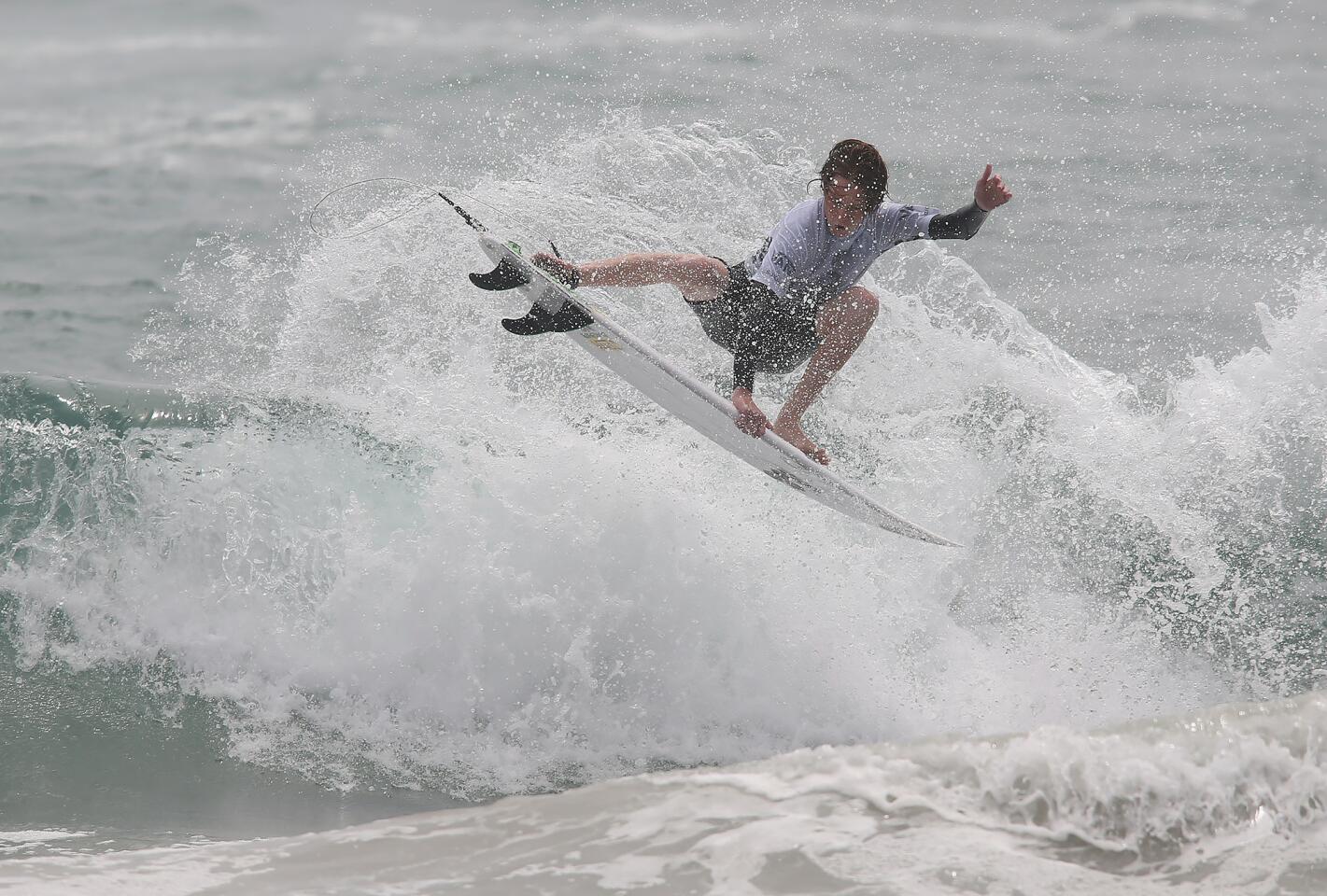 Jackson Butler completes an air move close to shore as he competes in the Junior Men's competition on the first day of the Van's U.S. Open of Surfing at the Huntington Beach Pier on Saturday.