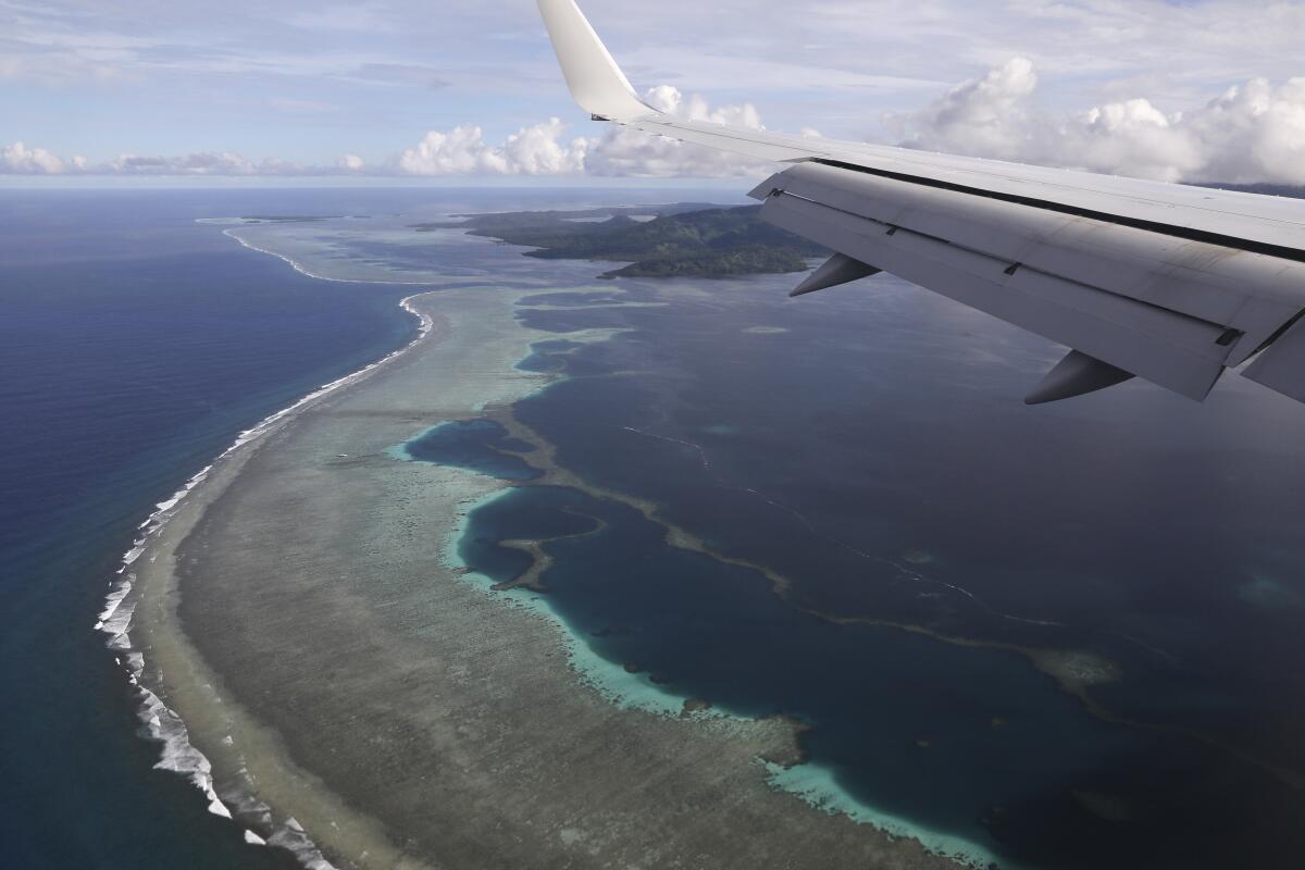 A plane wing over water and an island