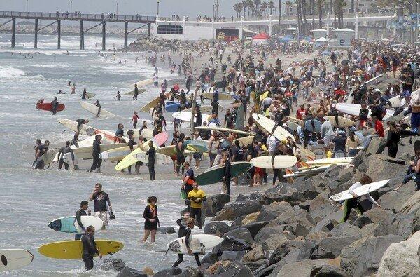 Surfers and spectators crowd The Strand, just south of the Oceanside pier to honor Junior Seau, a local NFL hero who died from a self-inflicted gunshot last week.