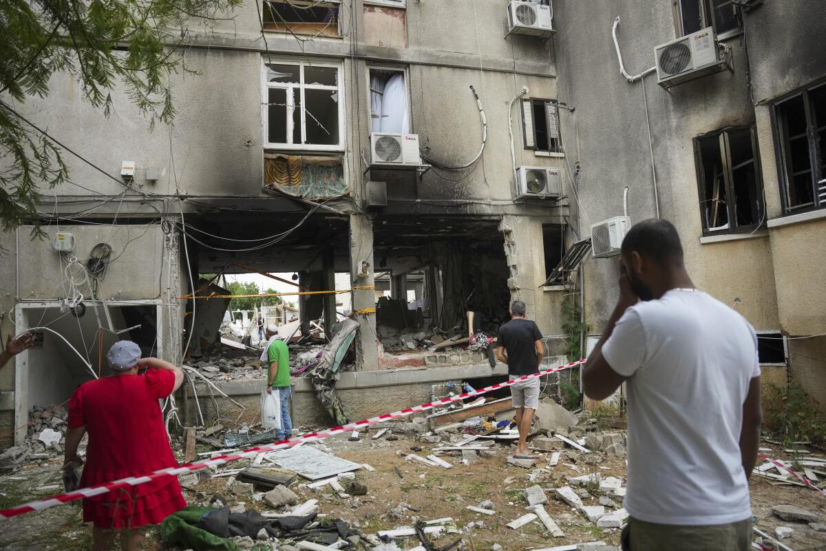 People looking at residential building damaged by Hamas rocket fire in Ashkelon, Israel