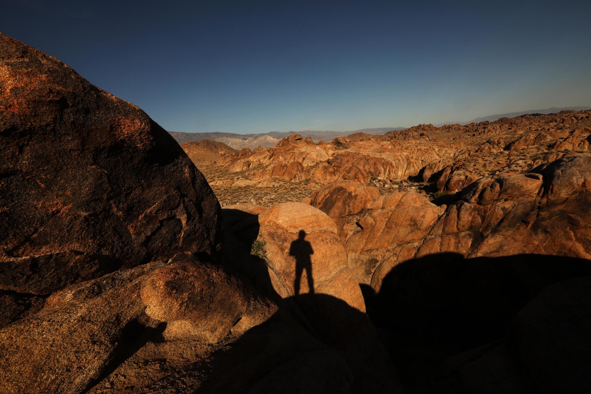 A shadow is cast against a rock formation in the Alabama Hills National Scenic Area by a man standing on a rock