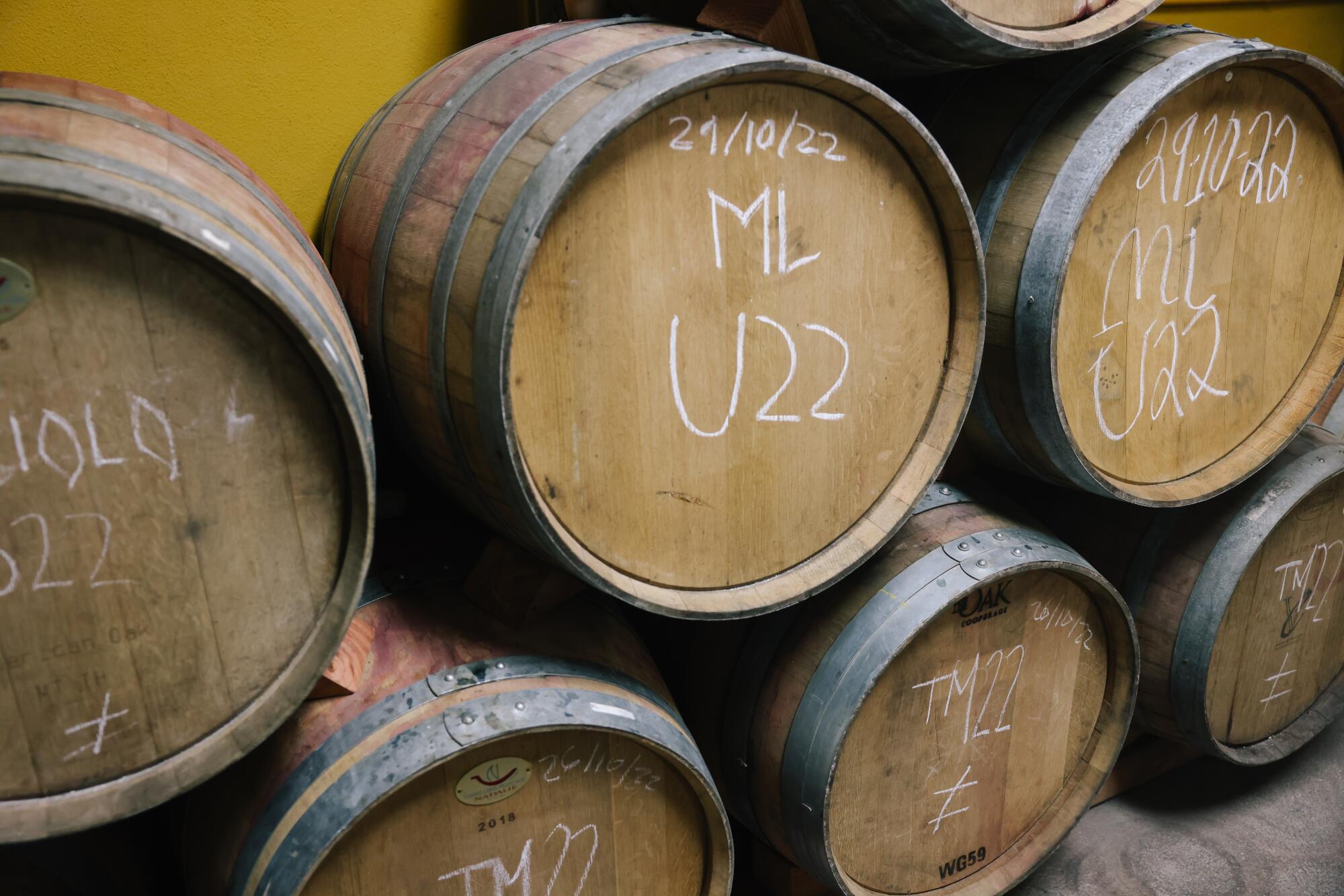 Oak barrels stacked up, with dates and numbers written on them.