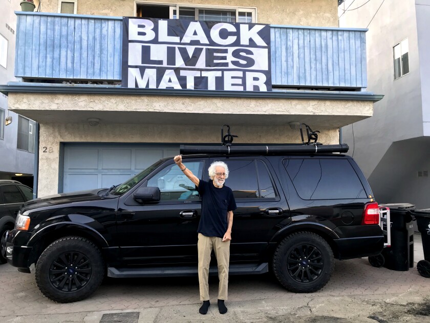 Robin Abcarian's father Richard Abcarian raising a fist in front of a Black Lives Matter banner.