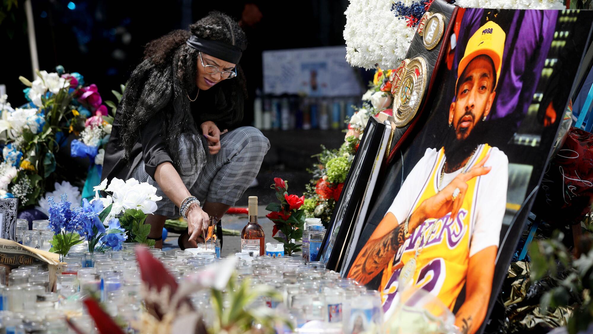Corina Samarco of Ypsilanti, Mich., lights a candle in the parking lot of the Marathon Clothing Company before the start of the Nipsey Hussle Celebration of Life procession on April 11.