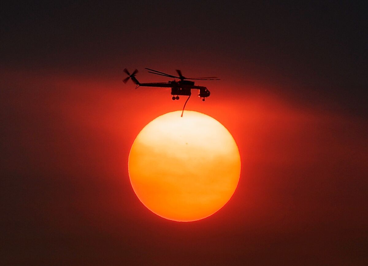 Smoke from the Mountain fire obscures the sun Thursday as a helicopter heads to battle the blaze.
