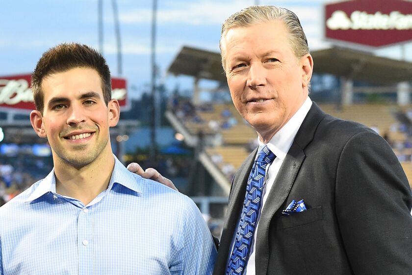 Dodgers broadcasters Joe Davis and Orel Hersheiser pose on the field together before a game against the San Francisco Giants in September 2016.