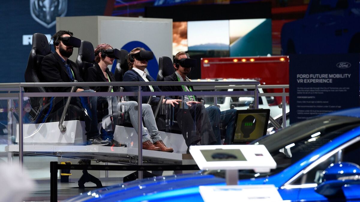 Attendees take part in a virtual reality ride in the Ford booth during the LA Auto Show at the Los Angeles Convention Center.
