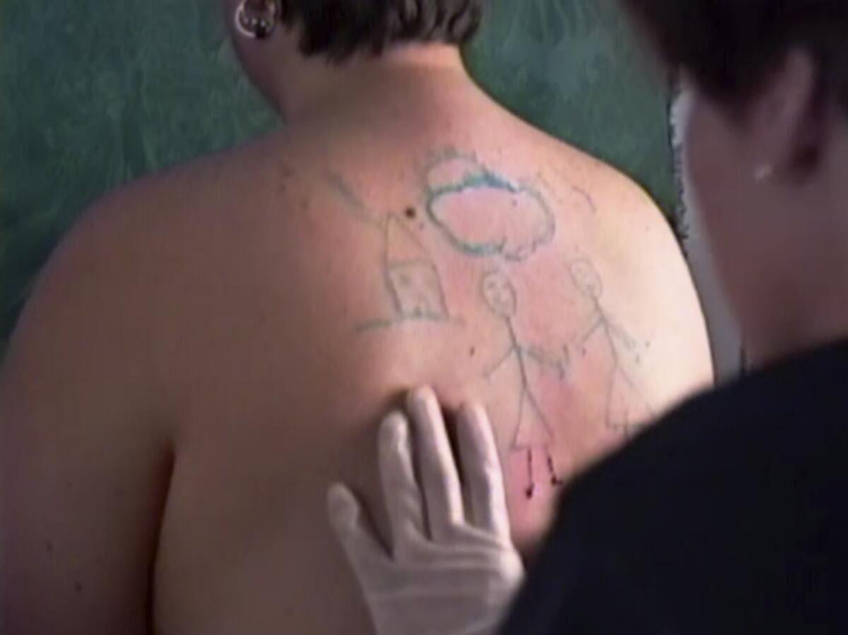 A documentary video shows a drawing being cut into photographer Catherine Opie's back.
