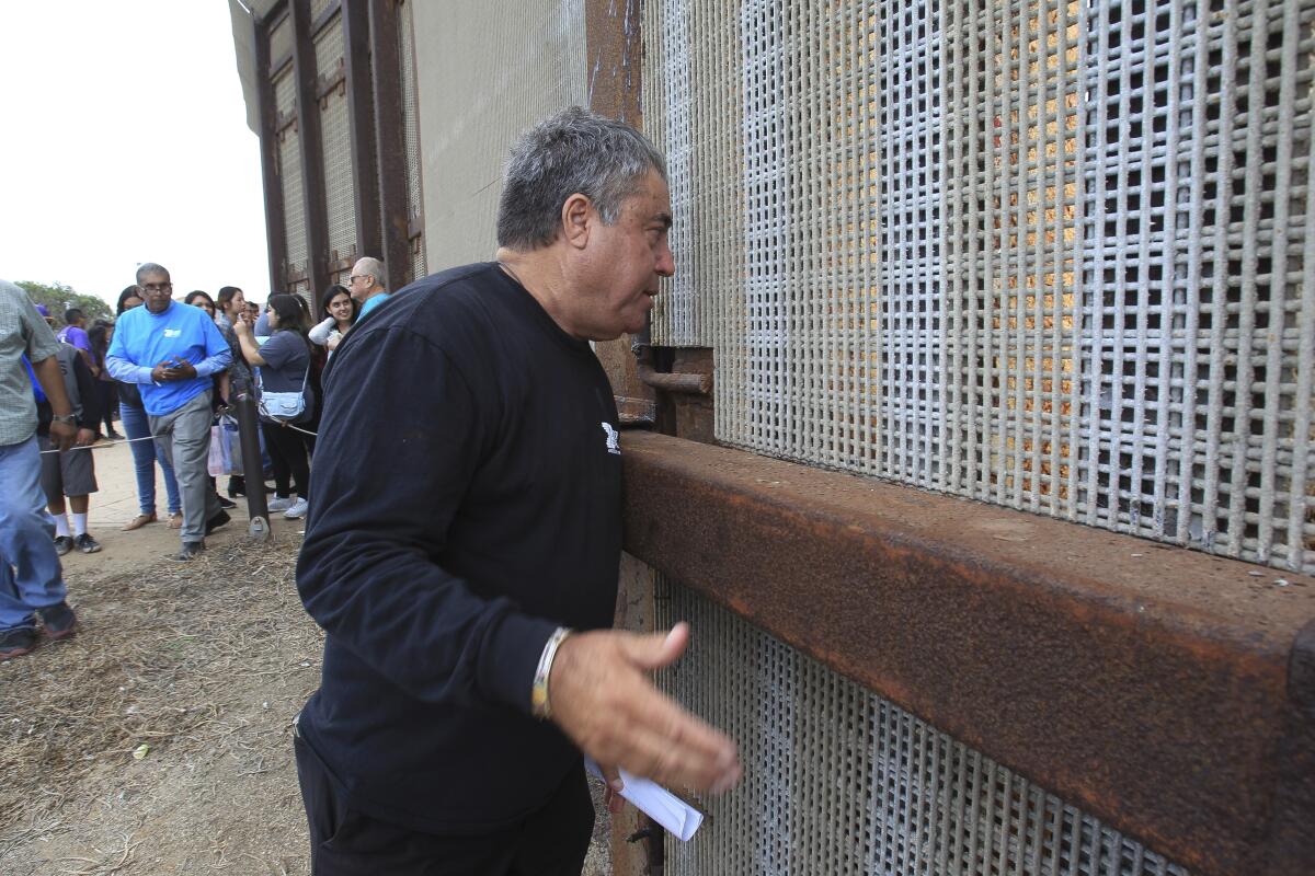 Enrique Morones talks to people on the Mexican side of the border fence