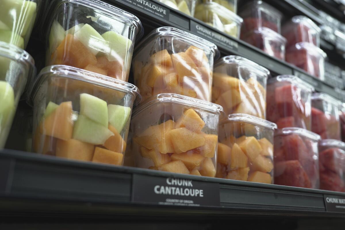 Containers of cantaloupe pieces are displayed for sale at a supermarket.