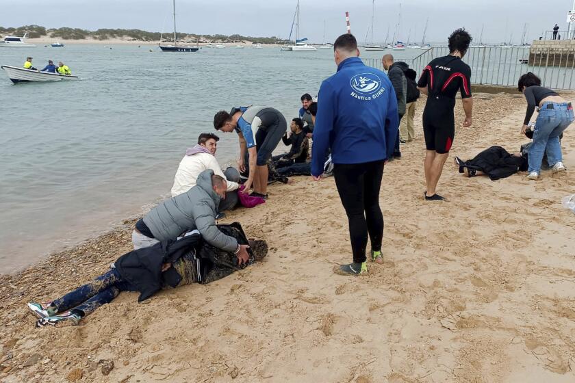 ARCHIVO - Migrantes son auxiliados por pobladores en una playa cercana a la ciudad de Cádiz, España, el jueves 30 de noviembre de 2023. (AP Foto/Jorge Gonzalez Casares, archivo)