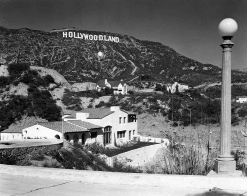 Circa 1926, a single-bulb streetlight with the Hollywoodland sign in the distance. 